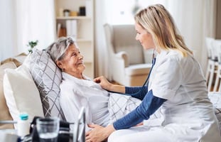 elderly patient having her heart checked by a nurse in a home settings